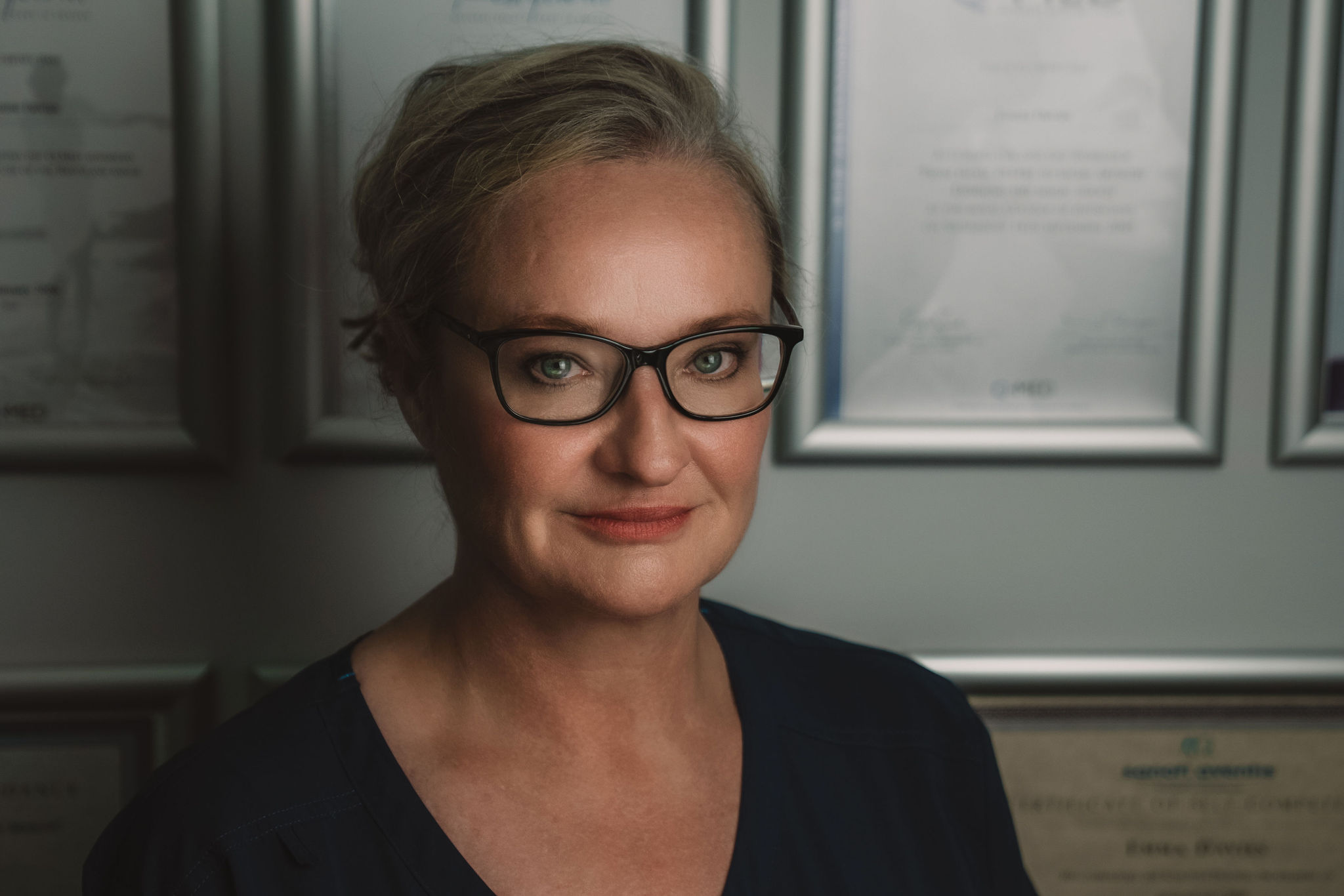Corporate headshot of a woman wearing glasses, in a professional office setting