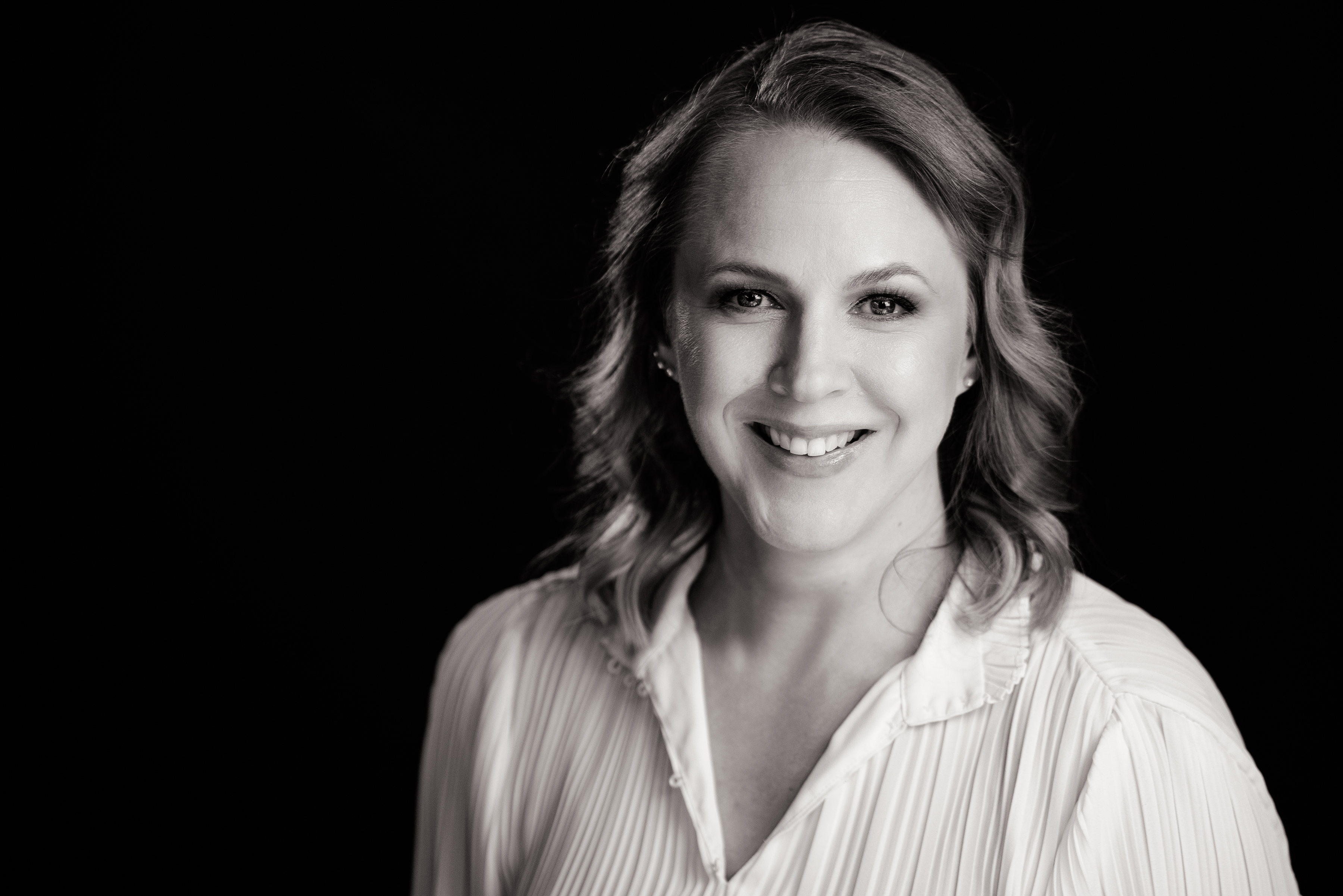 Professional portrait of a smiling woman in a white blouse, captured by Sonder Moments Media