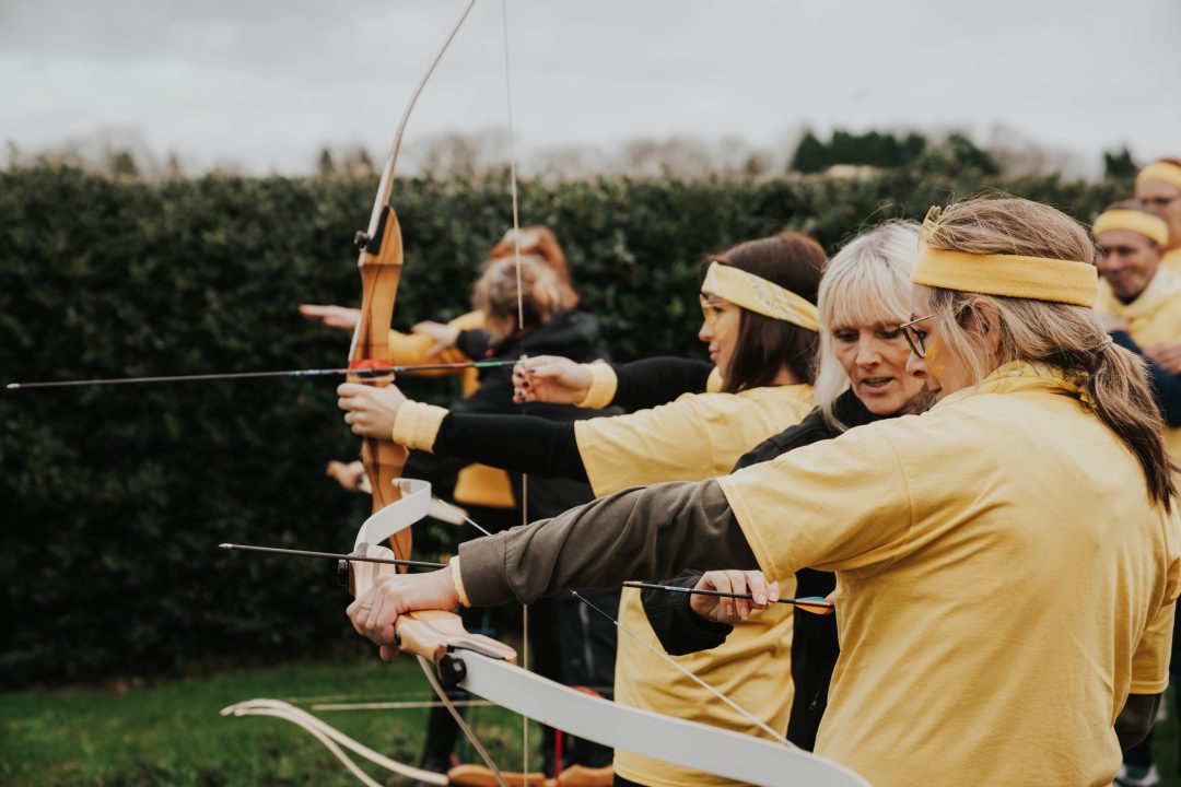 Group of women participating in an archery activity during a team event