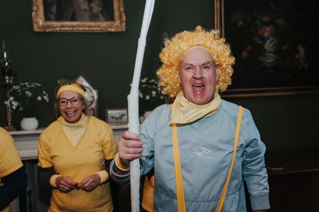 Man in a yellow wig cheering during a fun corporate event